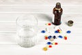 Close-up of bright colored medical tablets, a bottle of medicine and capsules with medicines and a glass of water. Scattered on