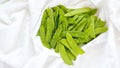 Close up of bright green snow peas on a white linen cloth