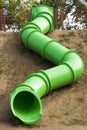A close-up of a bright, twisting pipe slide on a playground