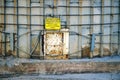 Close-up of a bright yellow caution sign hanging over a hatch at the base of an old concrete silo