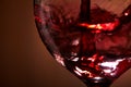 Close-up of brightly red wine poured in the wineglass and abstract splashing against brown background. Royalty Free Stock Photo