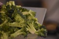 A close up of broccoli being chopped and prepared in a kitchen