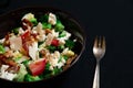Close-up Broccoli Salad with Bacon, parmesan cheese in a black plate. In the right a silver fork. Royalty Free Stock Photo