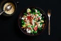 Close-up Broccoli Salad with Bacon, parmesan cheese in a black plate. In the right a silver fork.