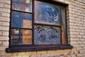 Close up of a broken boarded up window and sill with peeling paint and graffiti Royalty Free Stock Photo