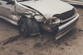 A close up of a broken car after a traffic accident in a overcast weather. Heavy damage of a bumper and a car wheel after a side-