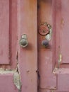 Close-up of broken and uncorked pink wooden door entrance with round door knobs. Old pink door with rusty and spoiled paint Royalty Free Stock Photo