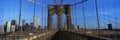 This is a close-up of the Brooklyn Bridge Walkway to Manhattan. The Manhattan skyline is in the background. The steel fencing is