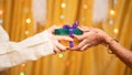 Close up of Brother Hands Giving gift to sister during during raksha Bandhan, Bhai Dooj or Bhaubeej Indian religious festival