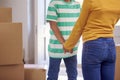 Close Up Of Brother And Sister Holding Hands Standing In Hallway Of New Home