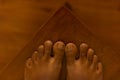 Close up of a brown asian feet, on a brown wooden background with Mortons toe.