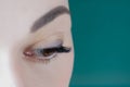 Close-up of brown eye with long eyelashes, black eyeliner, flawless eyebrow of unrecognizable young woman looking down, Royalty Free Stock Photo