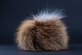 Close up of brown fox fur pompom. Blue background. Royalty Free Stock Photo