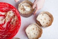 Close-up of brown paper baking tins filled with raw raisin dough and leveling it with a cooking muffin spoon at home Royalty Free Stock Photo