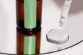 Close up of brown serum or oil glass with green stiker mock up on bottle on mirror background. Drops of liquid in a pipette Royalty Free Stock Photo