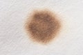 Close-up of brown stain on white textured surface representing cleanup and stain removal Royalty Free Stock Photo