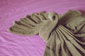 Close up brown towel plait as swan on purple bed Royalty Free Stock Photo