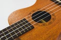 Close up of brown Ukulele on white background. Ukulele strings, saddle, soundhole, ukulele body, neck, fretboard. Royalty Free Stock Photo