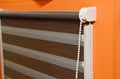 Close-up on a brown and white striped roller window blind on orange wall Royalty Free Stock Photo