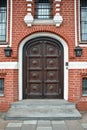 Close-up of a brown wooden front door on red brick wall home exterior Royalty Free Stock Photo