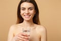 Close up brunette half naked woman 20s with perfect skin nude make up glass water isolated on beige pastel wall Royalty Free Stock Photo