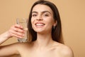 Close up brunette half naked woman 20s with perfect skin nude make up glass water isolated on beige pastel wall Royalty Free Stock Photo