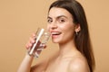 Close up brunette half naked woman 20s with perfect skin nude make up glass water isolated on beige pastel wall Royalty Free Stock Photo