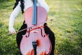 close up of a brunette woman with glasses playing cello at sunset in the park, on a green grass. Royalty Free Stock Photo