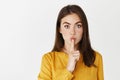 Close-up of brunette woman hushing, tell be quiet, share a secret and looking at camera, showing taboo sign while