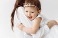 Close up of brunette young mother laying and holding baby girl. Attractive woman smiling and hugging her little daughter Royalty Free Stock Photo