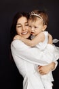 Close up of brunette young mother laying and holding baby girl. Attractive woman smiling and hugging her little daughter Royalty Free Stock Photo