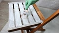 Close-up of a brush in hand and painting a wooden chair with white paint Royalty Free Stock Photo