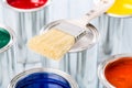 Close-up brush lying on multicolored paint cans