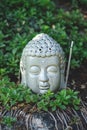 close up of Buddha head with aromatic smoking stick