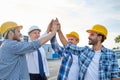 Close up of builders in hardhats making high five