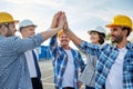 Close up of builders in hardhats making high five