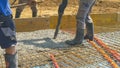 CLOSE UP: Builders pour the wet cement mixture over a layer of metal mesh.