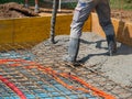 CLOSE UP: Builders are pouring cement mixture and leveling a house foundation.