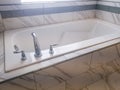 Close up of built in rectangular bathtub with stainless steel faucet and handles Royalty Free Stock Photo