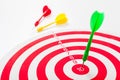 Close-up of a bull`s eye on a wall with three Darts, one dart hits the target, the others lie side by side Royalty Free Stock Photo