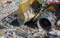 Close up of bulldozer working on the huge landfill or garbage dump pile, pollution concept