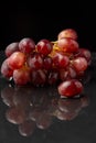 Close-up of bunch of red grapes on wet black slate, with reflection, on black background Royalty Free Stock Photo