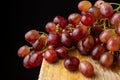 Close-up of bunch of wet red grapes, on rustic wooden table and black background, Royalty Free Stock Photo