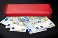 Close up of bundles of euro banknotes and opening a red wallet on a dark background. Selective focus Royalty Free Stock Photo