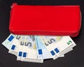 Close up of bundles of euro banknotes and opening a red wallet on a dark background. Selective focus Royalty Free Stock Photo