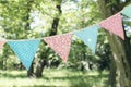 Close up of bunting flags hanging among trees. Summer garden party. Outdoor birthday, wedding decoration. Midsummer Royalty Free Stock Photo