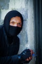 Close up a burglar wearing a mask holding a lock-picker to open a housedoor