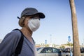 Close up of burnette woman wearing face mask with baseball cap in store parking lot