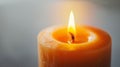Close-up of a burning candle with a warm flame, soft glow on a blurred background