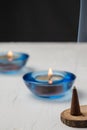 Close-up of burning incense on wood, candles with blue glass, selective focus, on white table, black background Royalty Free Stock Photo